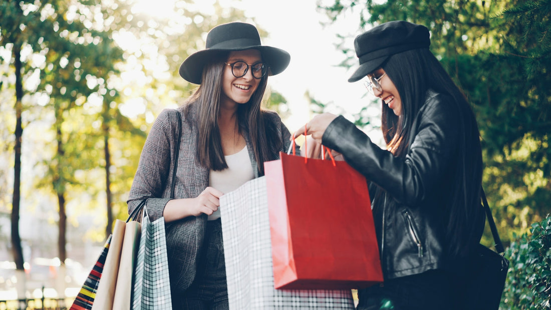 Two women looking into shopping bags outdoors