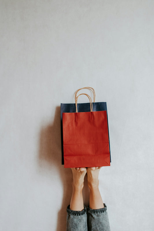 Hands holding shopping bags against a wall