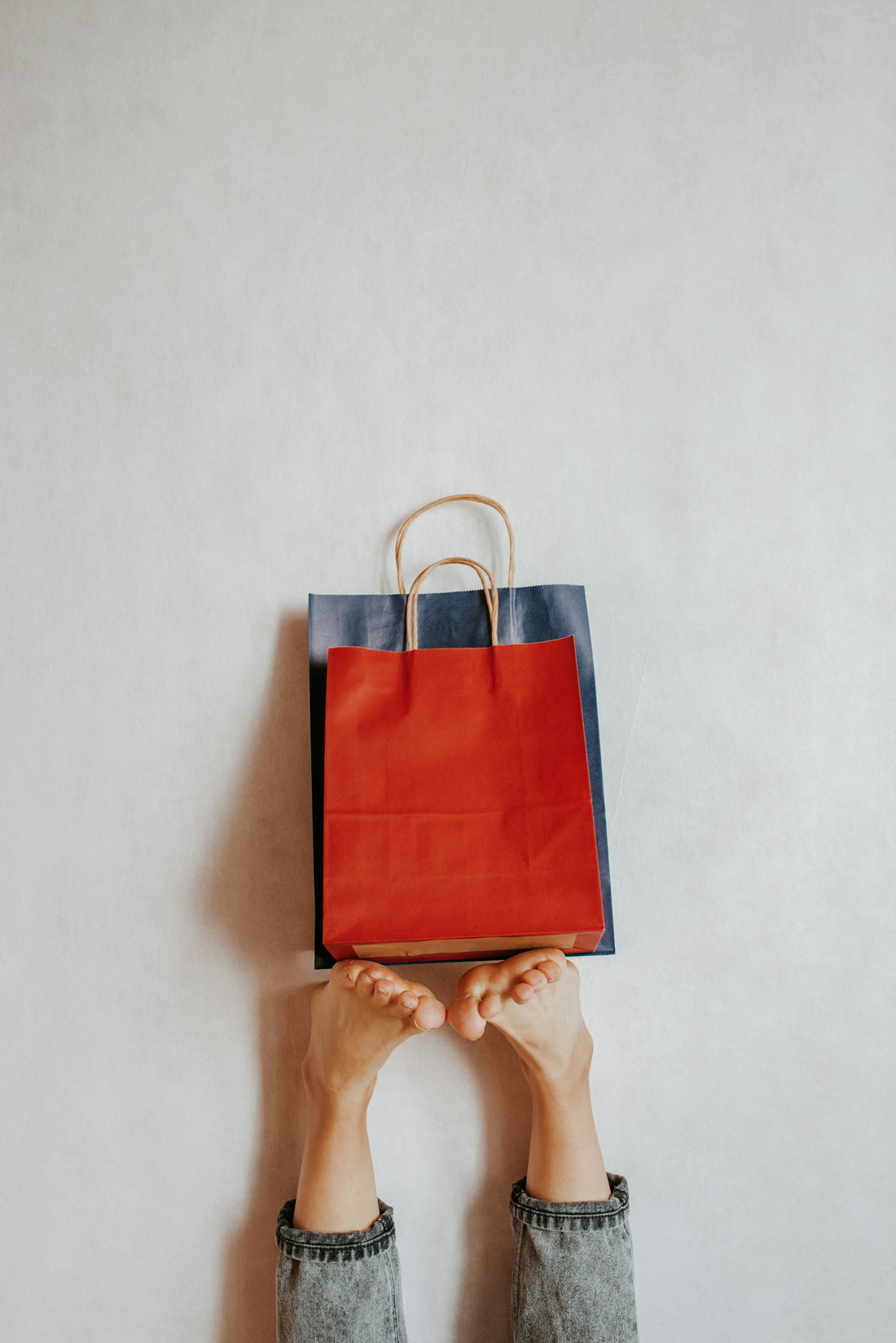 Feet holding shopping bags against a wall