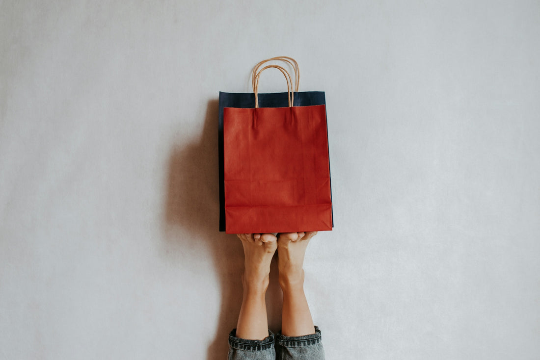 Hands holding a red shopping bag against a wall