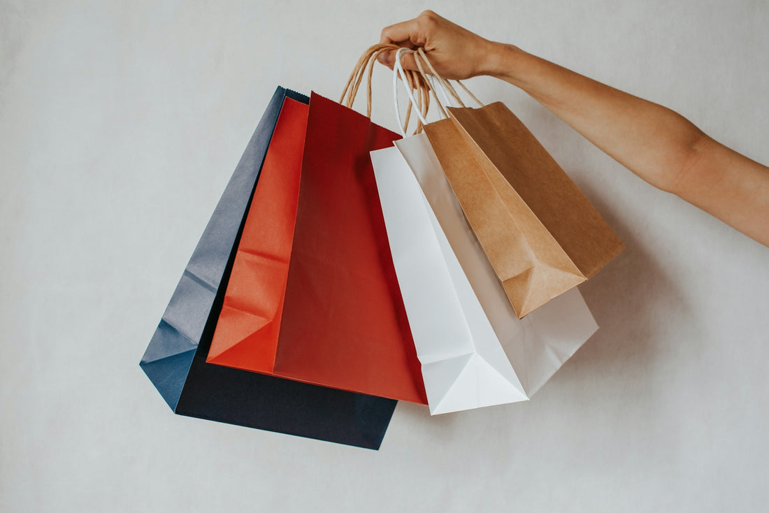 Hand holding colorful shopping bags against a white background