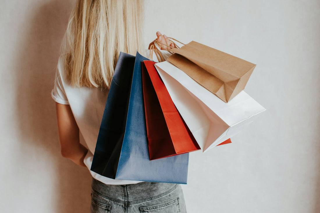Woman holding colorful shopping bags against a wall