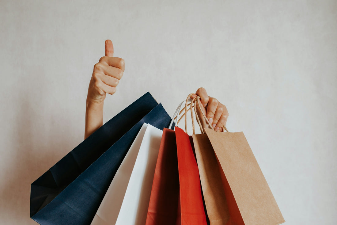Person holding shopping bags with a thumbs up