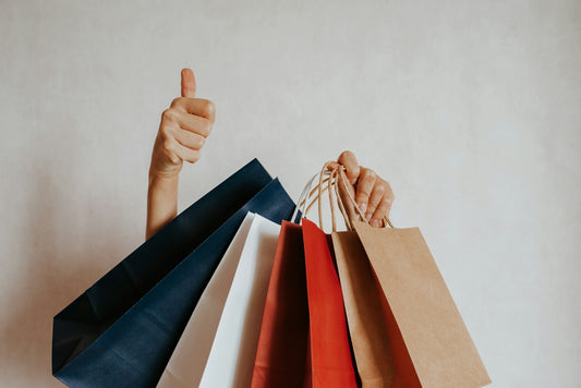 Person holding shopping bags with a thumbs up
