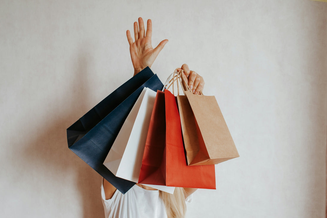 Person holding multiple shopping bags in front of white wall
