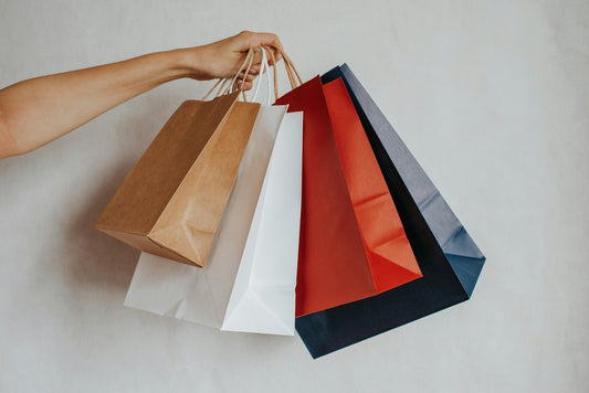 Hand holding colorful shopping bags against a light background