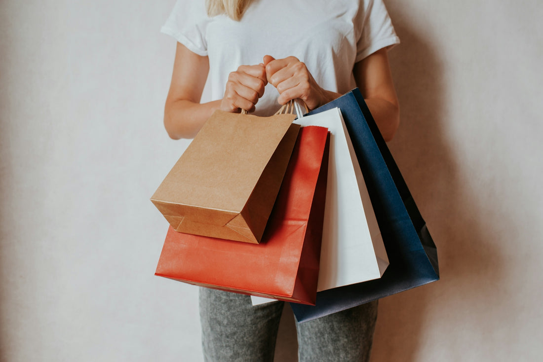 Woman holding shopping bags in front of white wall