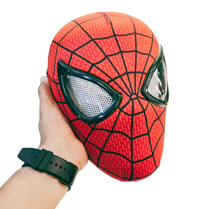 A red and black Spider-Man style plush mask being held by a person's hand against a plain white background.