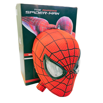 A plush Spider-Man mask in red and blue with black web patterns, positioned in front of its dark green and black retail box featuring 'The Amazing Spider-Man' text.
